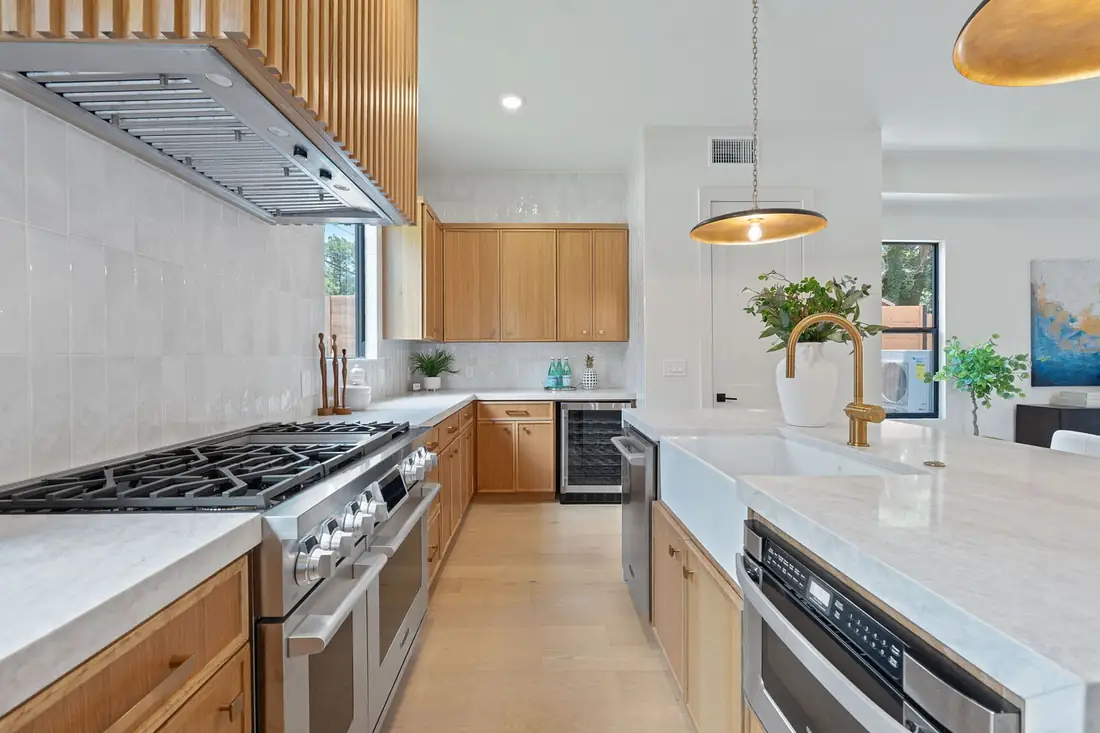 Oak kitchen with a six-burner range and stone backsplash in a Precise custom home