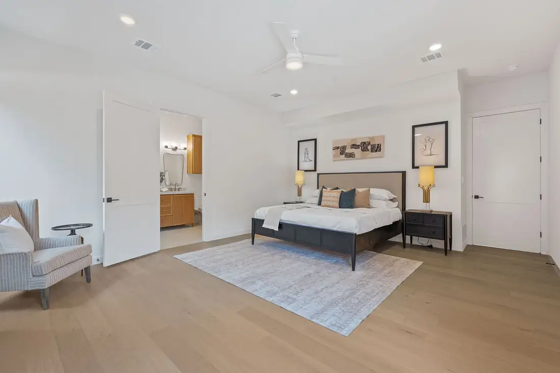 Primary bedroom with a tall window and soft neutral bedding