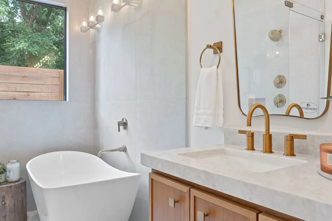 Freestanding soaking tub with a brass wall-mounted faucet