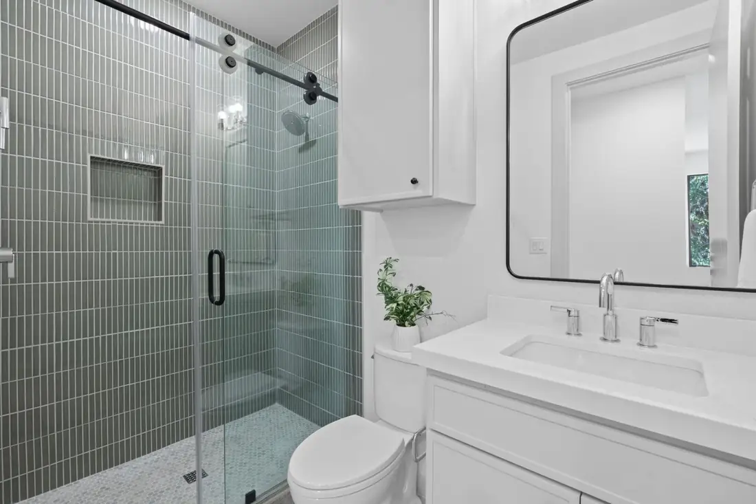 Green tiled walk-in shower with a glass door