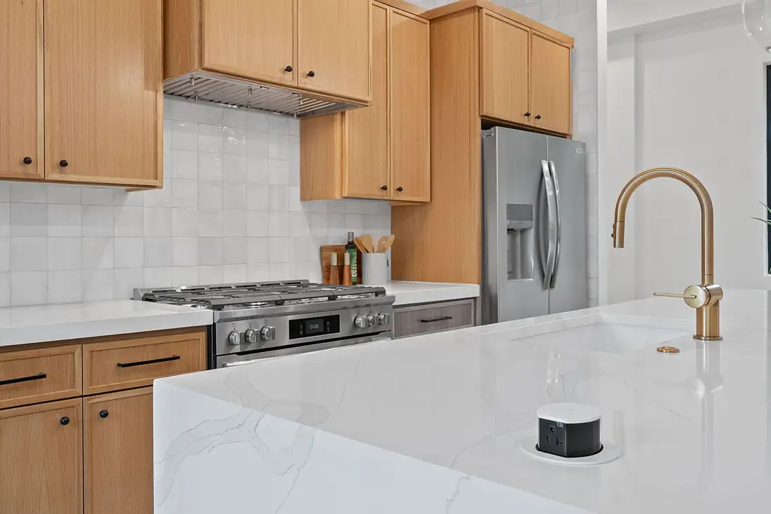 Oak cabinets and a gold faucet at a quartz island