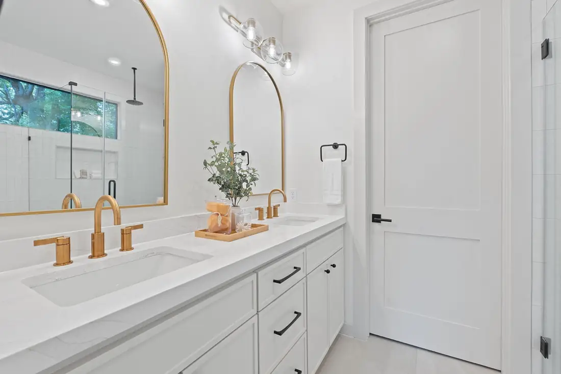 Arched mirror and brass fixtures over a white vanity