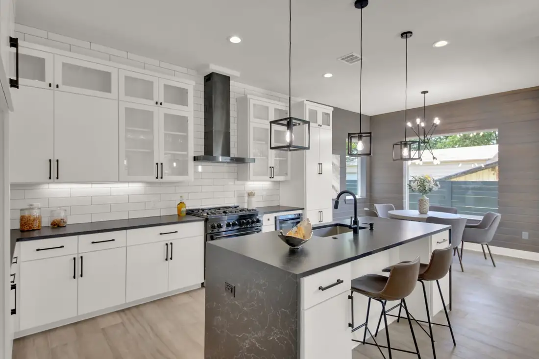 White shaker kitchen with a dark waterfall island and pendant lights